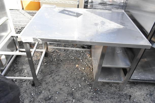 Stainless steel table with under shelves, featuring durable construction and spacious surface. Slight surface wear visible.
