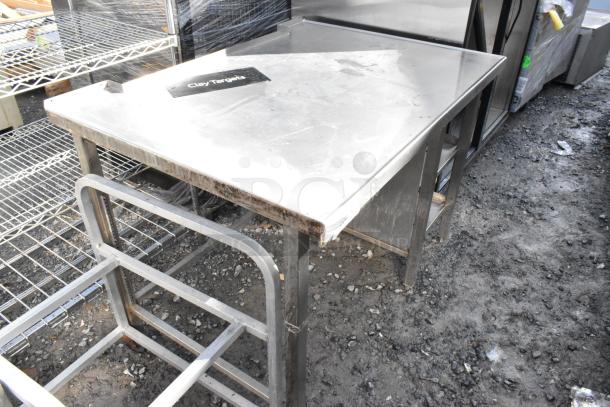 Stainless steel table with two under shelves, showing minor wear. Suitable for kitchen or workshop use. 