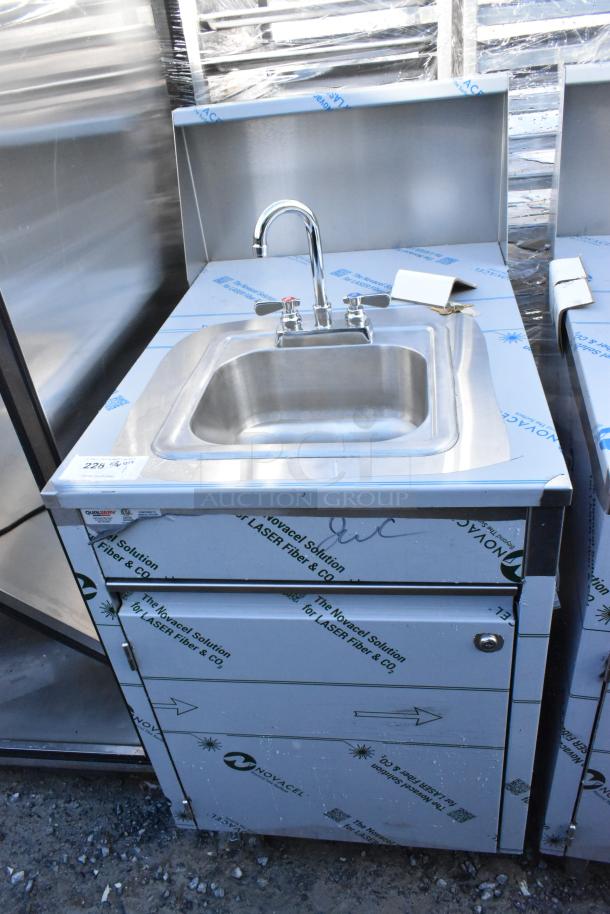 Brand new QualServ stainless steel portable sink with scratches, on commercial casters, protective wrap visible.