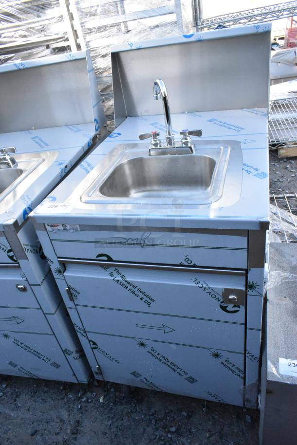 Brand new QualServ stainless steel portable sink on commercial casters, protective wrap, minor scratches and dents visible.
