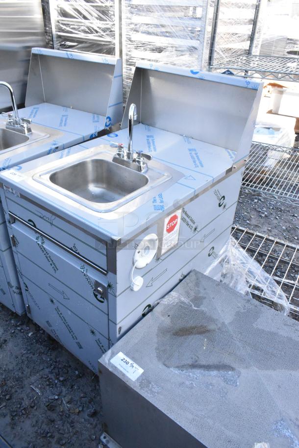 QualServ stainless steel portable sink on casters, new with minor scratches, features faucet, labeled instructions visible.