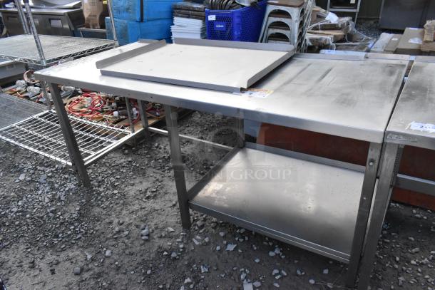 Stainless steel commercial table with under shelf, used condition, features backsplash, sturdy legs, ideal for kitchen use.