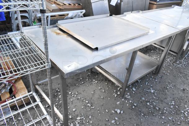 Stainless steel commercial table with under shelf, lightly worn. Ideal for food prep; durable and spacious. Visible item tag.