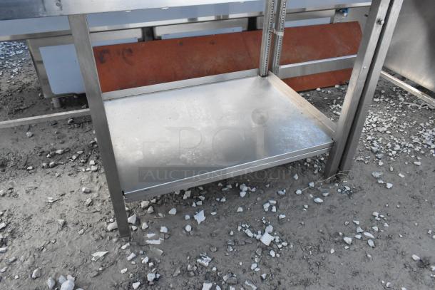 Stainless steel commercial table with under shelf, sturdy build, slightly scratched surface, suitable for kitchen use.