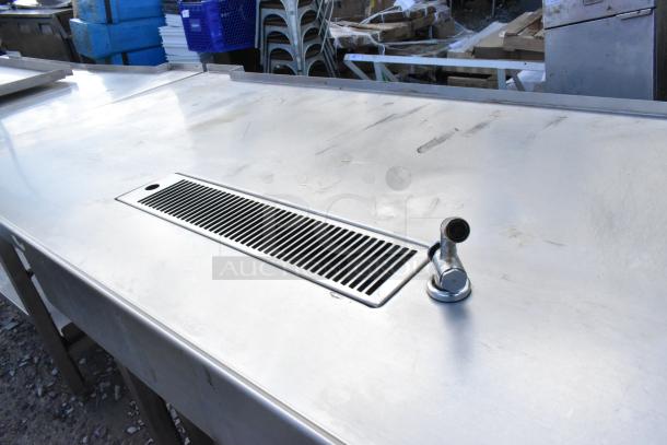 Stainless steel commercial soda station with integrated faucet and grate, featuring sturdy under shelves, in good condition.