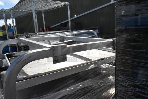 Two metal commercial pan transport racks with integrated baking pans, showing sturdy construction and practical design for professional kitchen use.