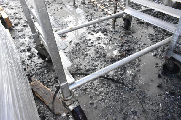 2 metal commercial pan transport racks with attached wheels and visible baking pan slots, shown in used condition.