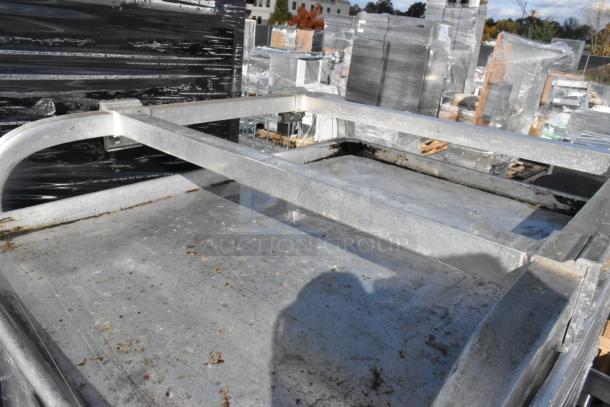 Two metal commercial pan transport racks with baking pans, visible wear, ideal for bakery or restaurant use.