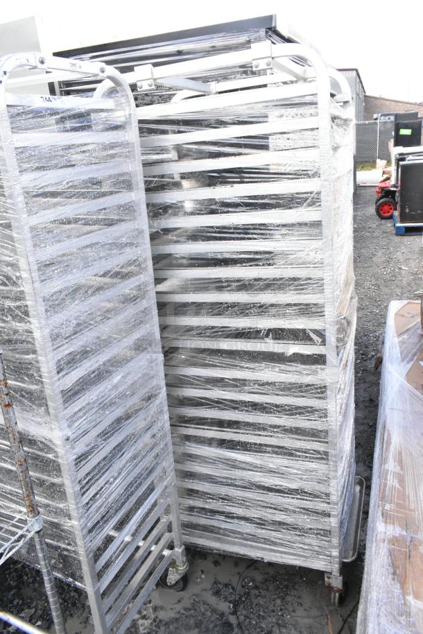 2 metal commercial pan transport racks with baking pans, wrapped in protective plastic, show ample storage capacity.