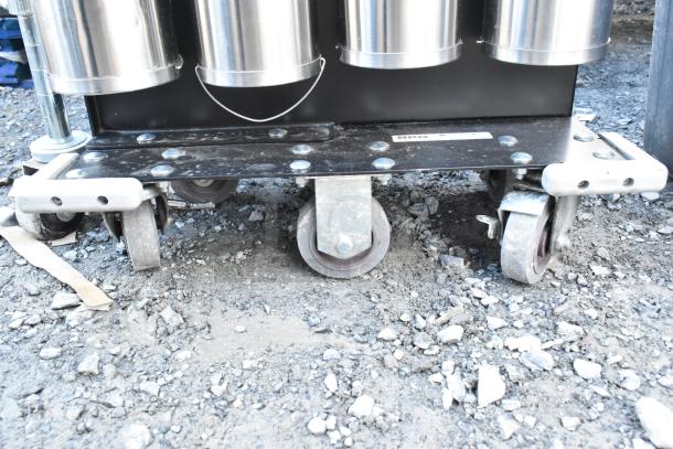 Metal 8 chute cup dispenser on commercial casters, featuring sturdy metal construction and a durable base, in used condition.