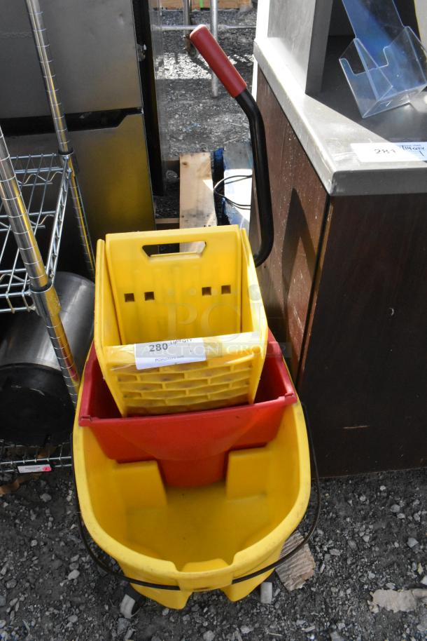 Yellow poly mop bucket with wringing attachment, handle, and wheels. Tagged with "280" from PCIauctions.com. Good condition.