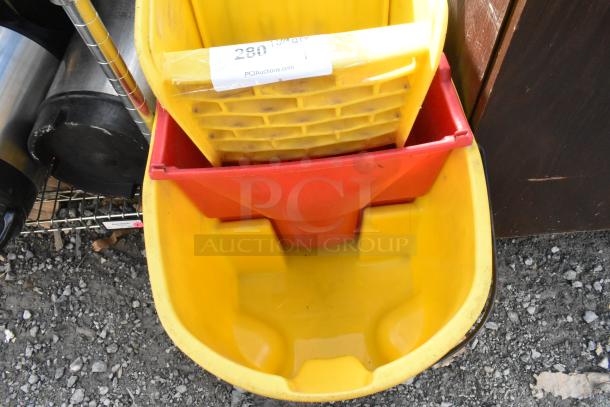 Yellow poly mop bucket with red wringing attachment. Marked "280" from PCIAuctions.com. Some dirt visible.