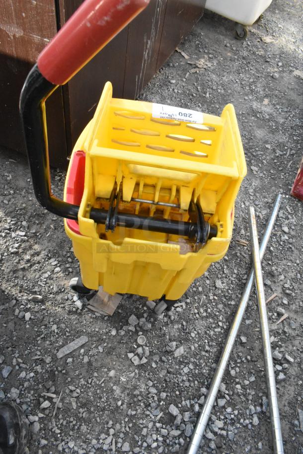 Yellow poly mop bucket with wringing attachment, good condition, red handle, label with auction details attached.
