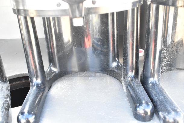 Close-up of metal beverage server satellite legs with reflective finish, showing minor wear and dust. Part of a four-item lot.