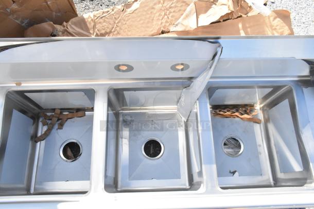 Brand new Regency 70" stainless steel 3-compartment sink with two drainboards, visible scratches, missing legs.