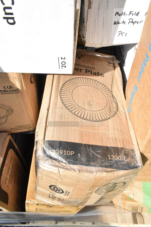 Sealed boxes of paper plates, cups, and paper goods with minor scratches and dents. Multifold paper towels visible.