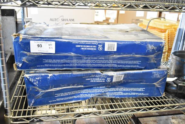 Two boxed Oster F227JN countertop heated food warmers, slightly worn packaging, with visible product labels and auction tag.