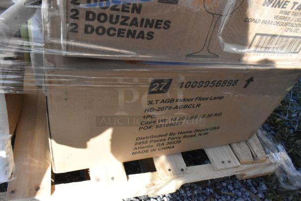 Boxes of assorted items including wine glasses and burger press, labeled as scratch and dent, distributed by Home Depot USA.