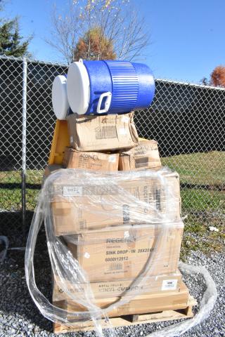 Stack of brand new scratch and dent items, including Igloo beverage coolers, platters, sink, and cushions, wrapped on a pallet.
