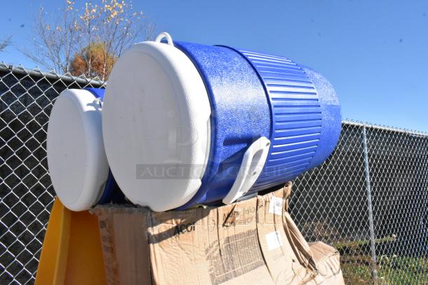Brand new Igloo beverage coolers, blue and white, scratch and dent condition, on a cardboard box.