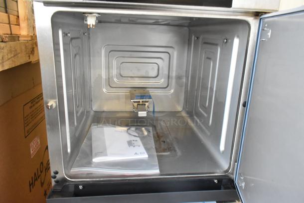 Brand new Alto Shaam 1750-SK stainless steel commercial smoker oven, open interior view, with manual in plastic bag.