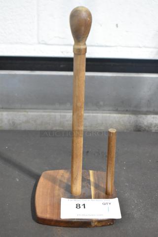Brand new wooden paper towel holder with scratches and dents, features a sturdy base and vertical dowel. Auction tag shows "81 QTY 1".
