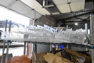 Tiered lot of poly drink sliders on industrial shelves in a warehouse. Includes multiple items for auction.