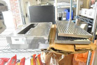 Five new scratch and dent drip trays and stainless steel panels stacked. Tag indicates quantity 5 for auction.