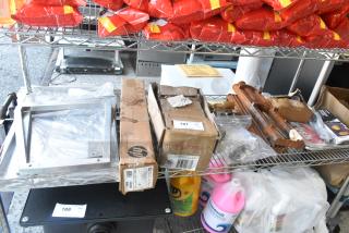 Tiered shelf with HP Bright White Inkjet Paper, UPR6GE plates, metal pieces, assorted items in boxes and bags.
