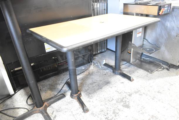 Wood pattern dining table with two black metal bases, rectangular top, slight edge wear, used condition.