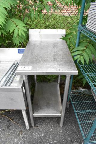 Stainless steel table with a metal under shelf, used condition. Features a back splash, ideal for kitchen or industrial use.