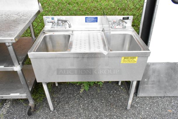 LaCrosse Stainless Steel 2 Bay Sink w/ Drain Board, Splash Guard and 2 Faucets. - Image 1 of 6