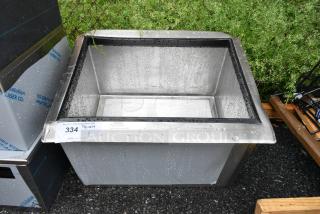 Brand new stainless steel drop-in bin with minor scratches and dents, water droplets visible, auction tag labeled "334".