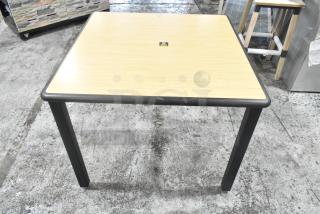 Dining height table with a light wood top and black edge. Features four black legs and a central square marking. In good condition.