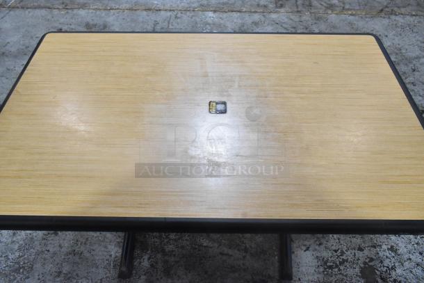 Dining table with wooden top and black metal base, used condition, surface wear visible.