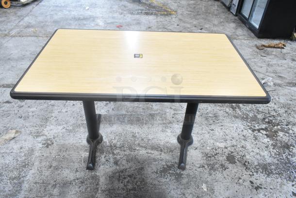 Dining height table with light wood top, black metal base, in used condition. Auction includes five tables per bid.