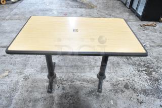 Dining height table with light wood top, black metal base, in used condition. Auction includes five tables per bid.