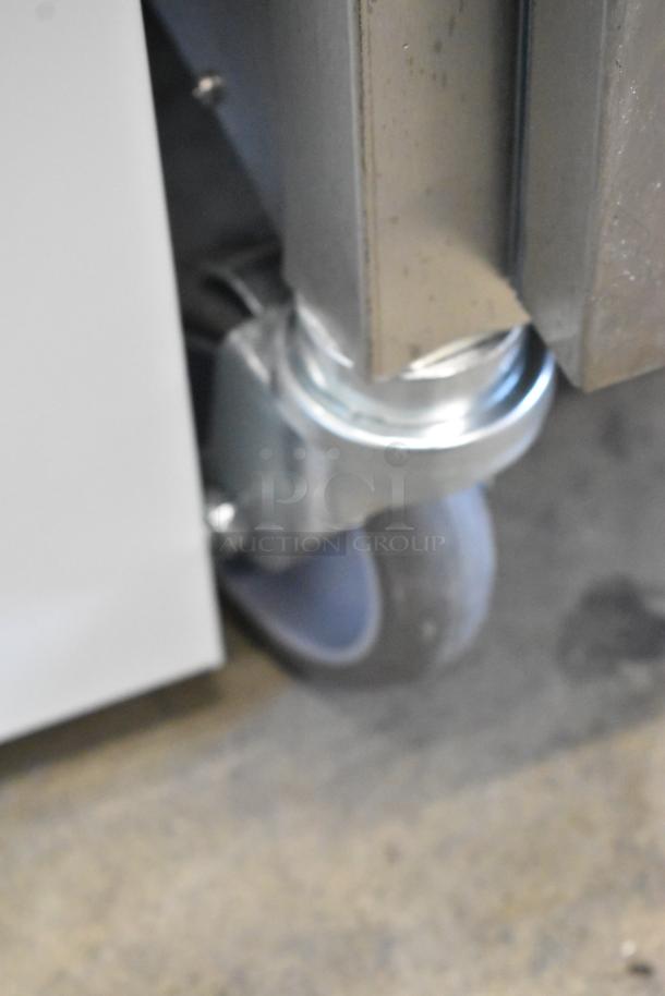 Stainless steel wheel and corner of Alto Shaam 1200-UP holding cabinet on caster. New condition, minor scratches.