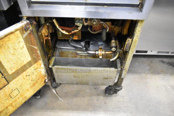 Henny Penny 600 pressure fryer, stainless steel, natural gas, 80,000 BTU, commercial casters, visible wear and rust.
