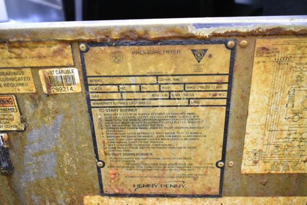 Henny Penny 600 stainless steel pressure fryer, natural gas, 80,000 BTU, on commercial casters. Labels show model and instructions.