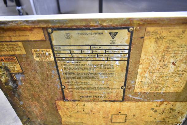 Henny Penny 600 Pressure Fryer label showing model, natural gas use, 80,000 BTU, and maintenance instructions. Rust visible.