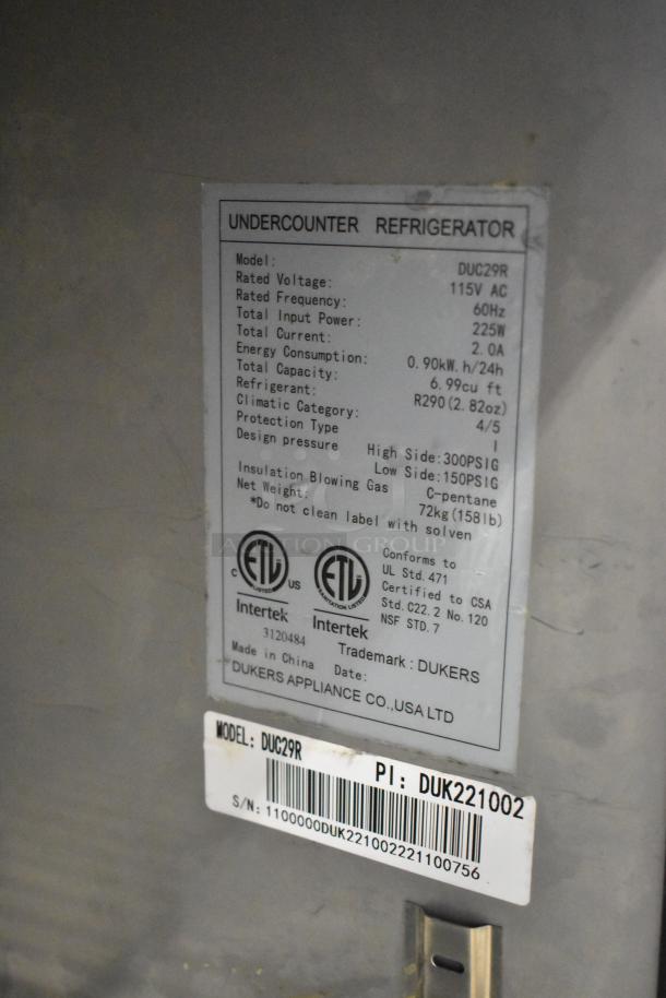 Dukers DUC29R stainless steel undercounter cooler, 115V, commercial casters, tag shows specifications and certifications.
