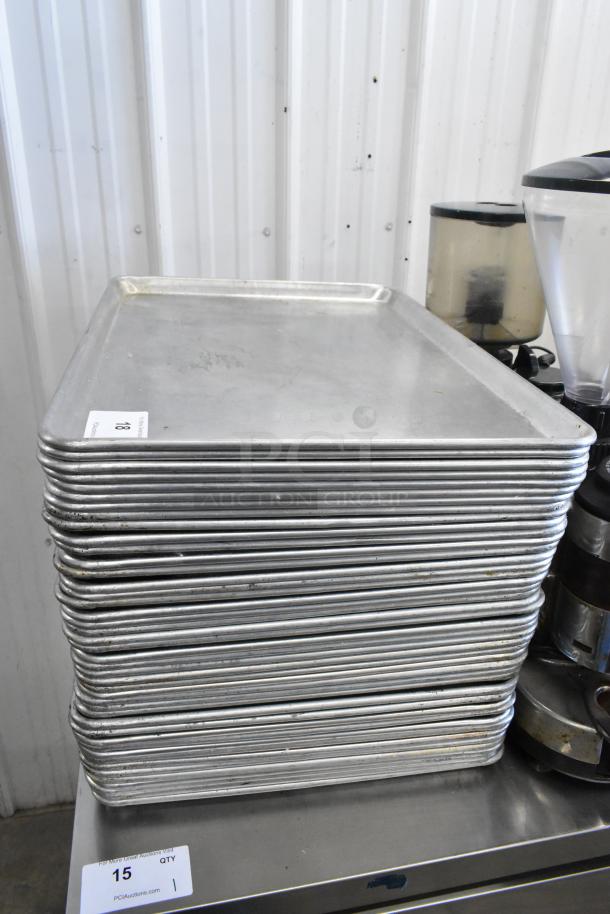 Stack of 42 metal full-size baking pans, used condition, auction lot tag visible with quantity "15" noted.