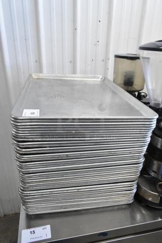 Stack of 42 metal full-size baking pans, used condition, auction lot tag visible with quantity "15" noted.