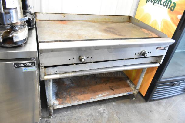 Tri-Star Stainless Steel Commercial Griddle on equipment stand, used condition, visible wear on surface, dual control knobs.