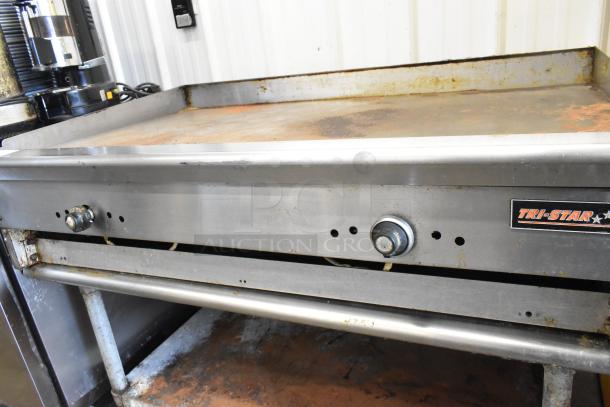 Tri-Star stainless steel commercial countertop flat top griddle on equipment stand. Visible wear, durable industrial build.