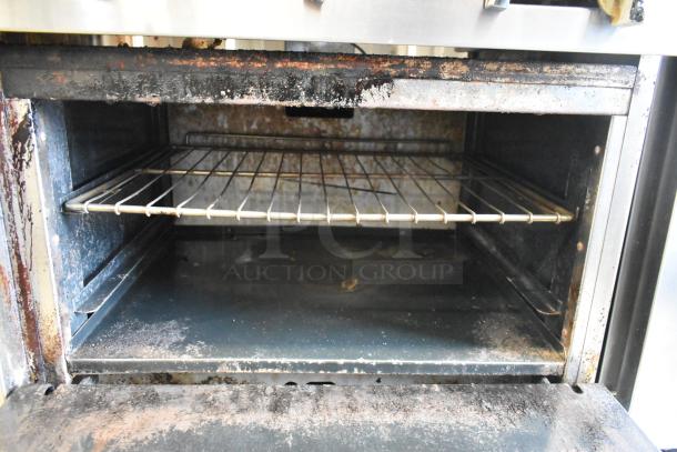 American Range stainless steel 6 burner commercial gas range. Features salamander cheese melter, backsplash, and oven. Used condition.