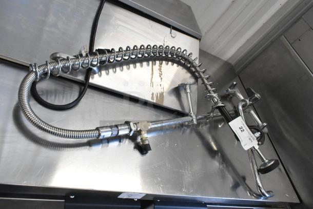 Chrome spray nozzle attachment with faucet, coiled hose, and wall mount. Includes visible tag marked "22." Appears in good condition.