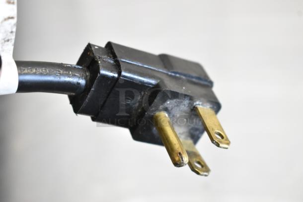 Close-up of an electrical plug from a Beverage Air SPE48HC-08 prep table. Black plastic casing with two brass prongs.