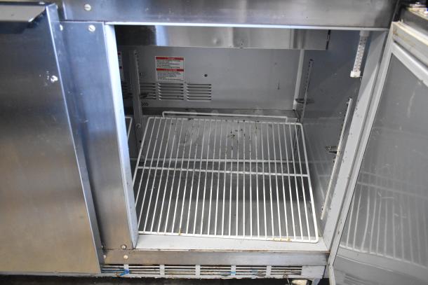 Beverage Air SPE48HC-08 stainless steel prep table, open door view showing wire shelf. Used condition, commercial casters visible.